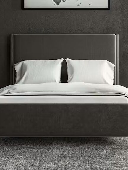 A modern bedroom with a dark gray bed, white bedding, two bedside tables with gold lamps, and floor-to-ceiling curtains.