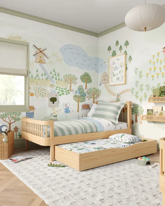 Children’s bedroom with a wooden bed and pull-out trundle, striped bedding, and playful nature-themed wall murals featuring animals, trees, and a windmill. Natural light from window.