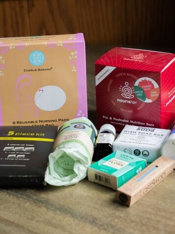 A variety of maternity and baby care products, including nursing pads, nutrition bars, wipes, supplements, cream, and other health essentials, arranged on a wooden surface.