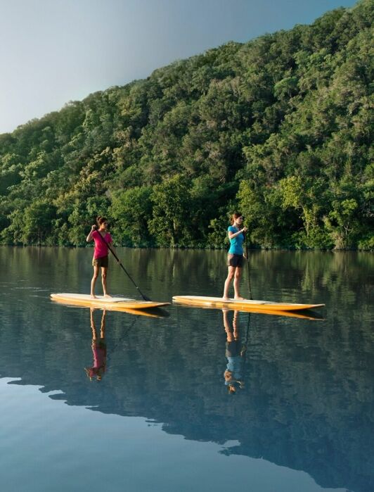 Two people paddle boarding at Lake Austin Spa Resort. 