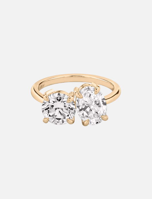 Gold ring with two large adjacent gemstones, one round and one oval.