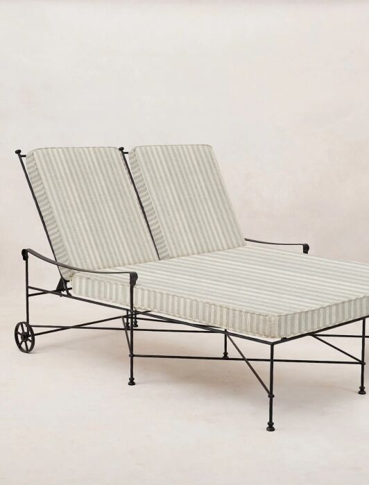 A double outdoor lounge chair with a black metal frame and two adjustable striped cushions, set against a plain light background.