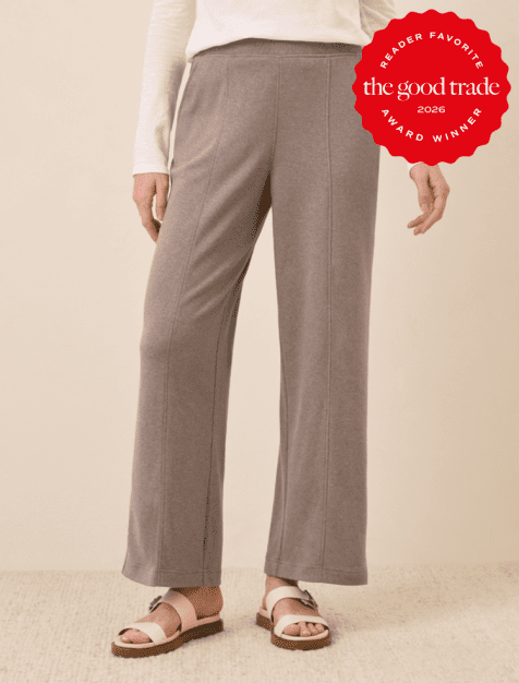 Person wearing grey wide-leg knit pants, a white long-sleeve top, and beige sandals. A red "The Good Trade Award Winner 2026" badge is in the top right corner.